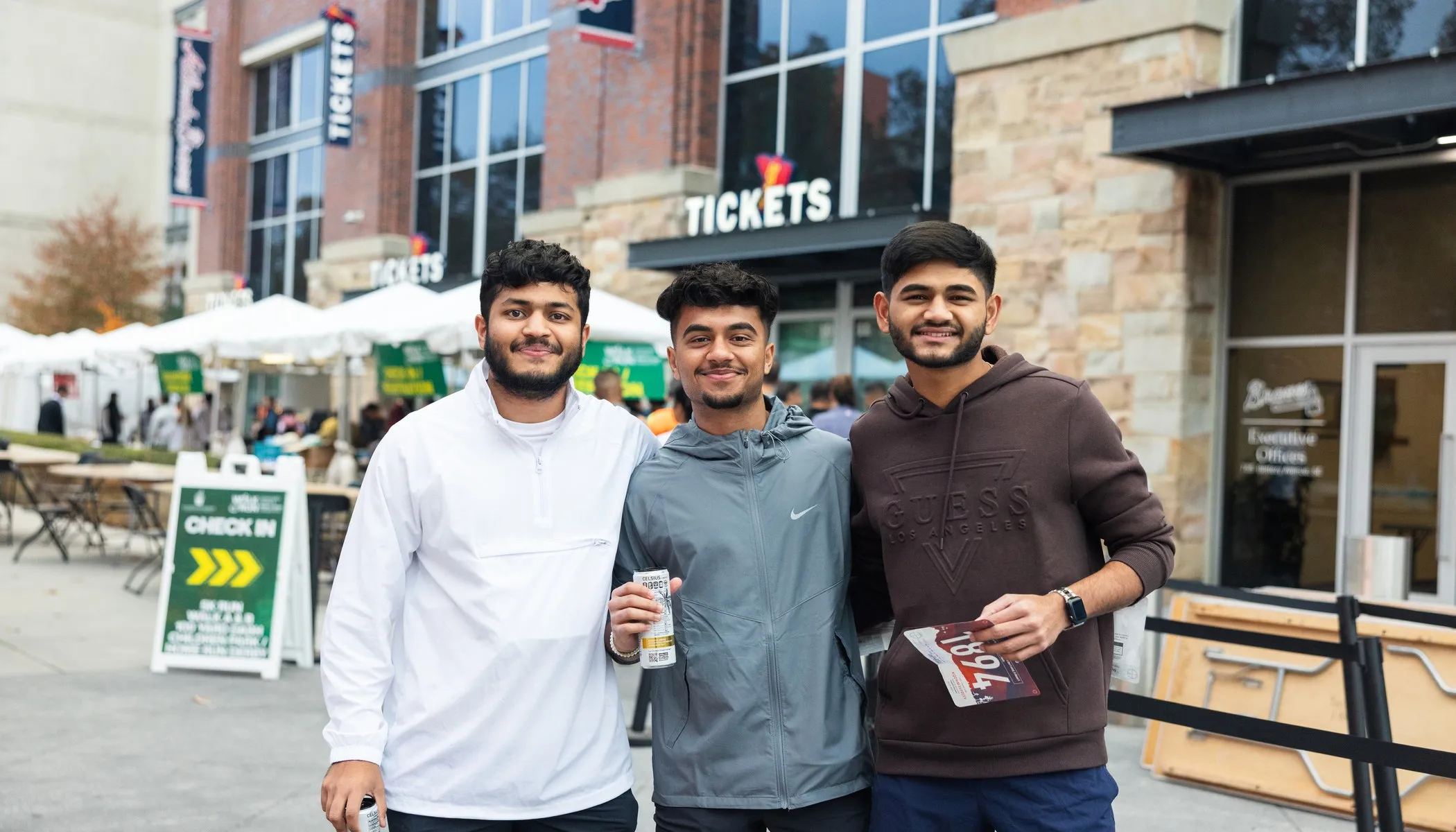Three friends holding their race bibs outside the Truist Park ticket gate